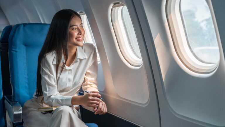 Asian,Woman,Sitting,In,A,Seat,In,Airplane,And,Looking